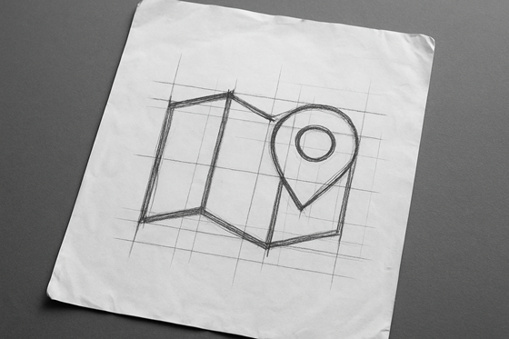 A photograph of a slightly worn, wrinkled blank sheet of white paper that lays flat, slightly tilted, on a table. On the paper is an icon of a map.