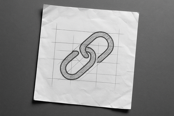 A photograph of a slightly worn, wrinkled blank sheet of white paper that lays flat, slightly tilted, on a table. On the paper is an icon of a link.