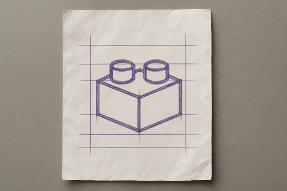 A photograph of a slightly worn, wrinkled blank sheet of white paper that lays flat, slightly tilted, on a table. On the paper is an icon of a building block.